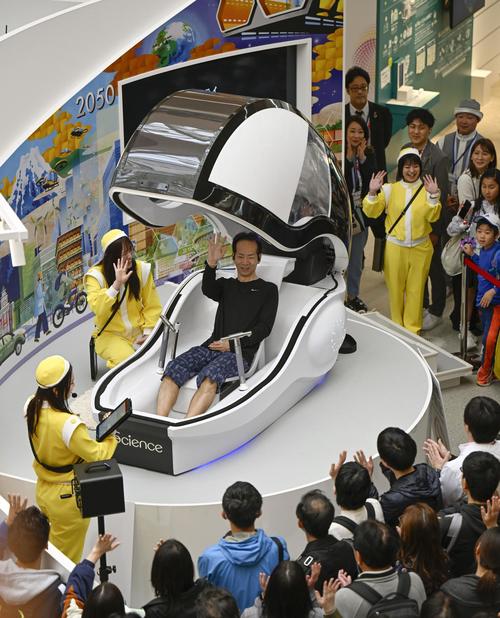 大阪ヘルスケアパビリオンで「ミライ人間洗濯機」を体験する来場者(共同)