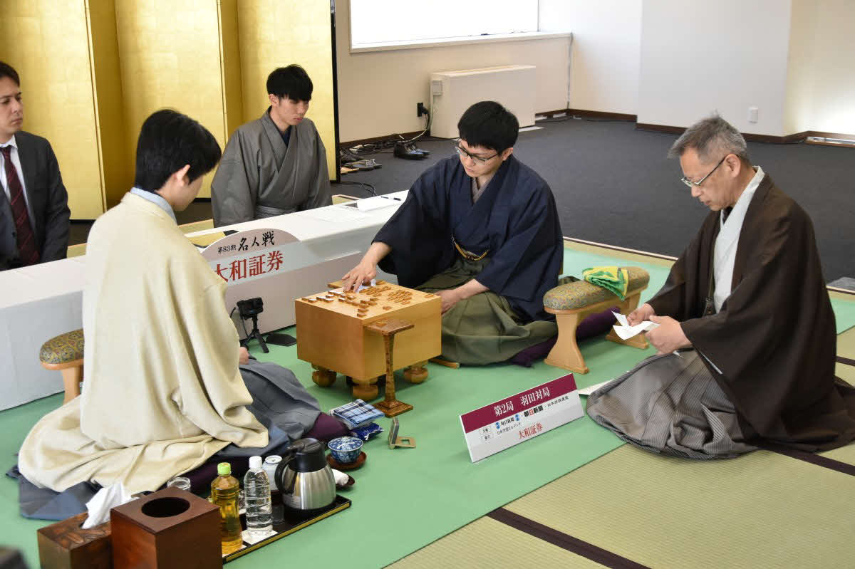藤井聡太名人（左）に永瀬拓矢九段（中央）が挑む名人戦第2局は立会人の中村修九段（右）が封じ手を開封して2日目が再開された（日本将棋連盟提供）