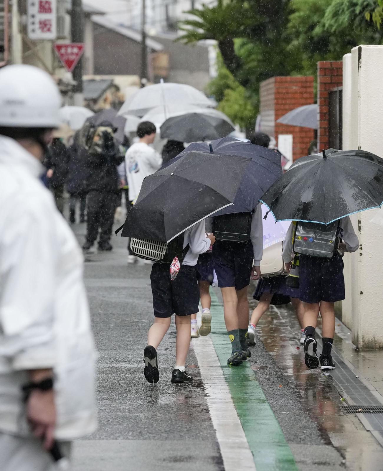 小学生が故意に車ではねられた事件から一夜明け、大阪市立千本小に手をつないで登校する児童＝2日午前、大阪市西成区（共同）