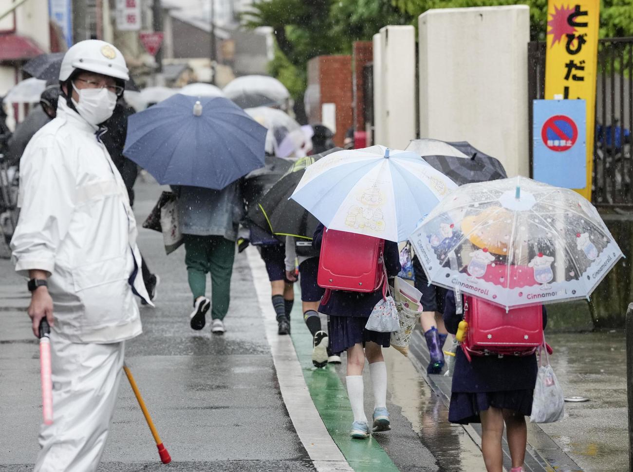 小学生が故意に車ではねられた事件から一夜明け、大阪市立千本小に手をつないで登校する児童＝2日午前、大阪市西成区（共同）