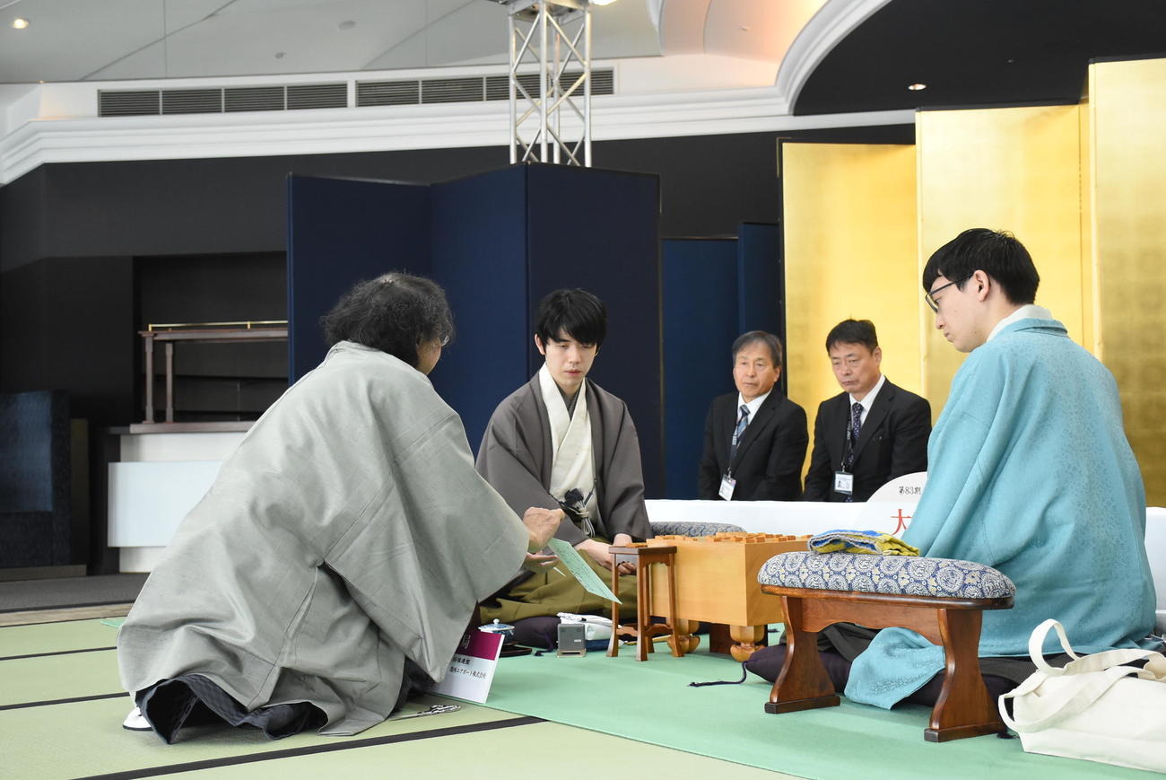 名人戦7番勝負第3局2日目、封じ手を確認する藤井聡太名人（左）永瀬拓矢九段、中央は立会人の福崎文吾九段（日本将棋連盟提供）