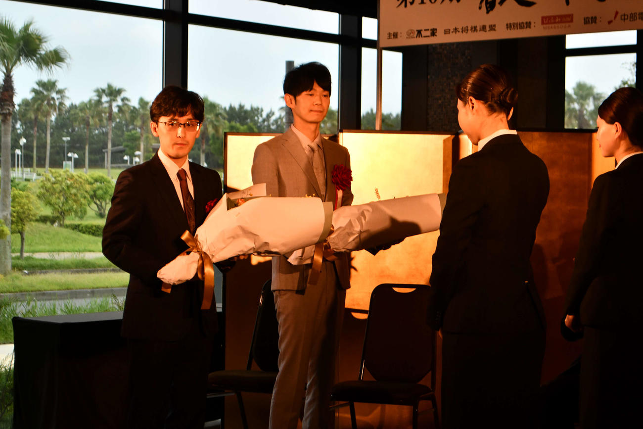対局会場となるホテルのスタッフから花束を贈呈された伊藤匠叡王（左）と挑戦者の斎藤慎太郎八段