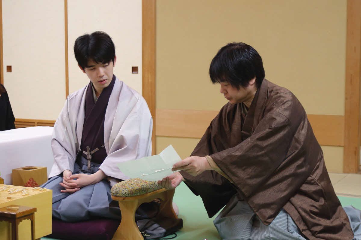 藤井聡太名人（左）は立会人の藤井猛九段が開封した封じ手を確認する（日本将棋連盟提供）