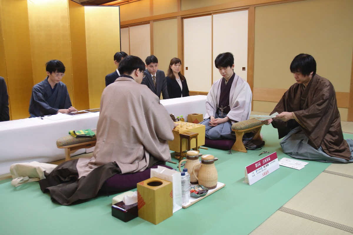 永瀬拓矢九段（左）の封じ手を開封する立会人の藤井猛九段（右、中央は藤井聡太名人＝日本将棋連盟提供）
