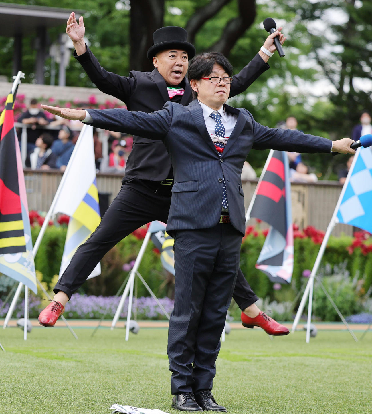 日本ダービーに小泉進次郎農相が来場したこともあり、全レース終了後のトークショーで、観客に観客に「米ポーズ」をプレゼントするTIMのレッド吉田（手前）とゴルゴ松本（撮影・野上伸悟）