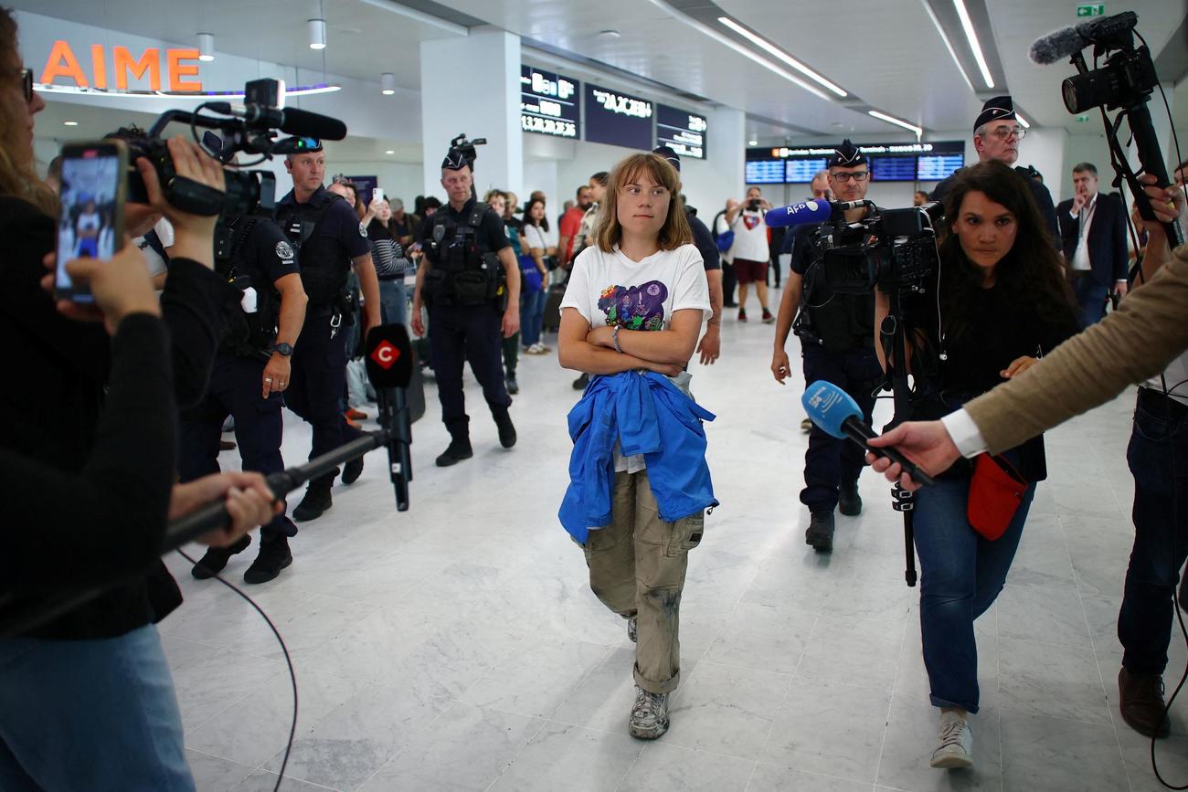 イスラエルからスウェーデンに戻る経由地のパリ、シャルル・ド・ゴール空港を記者や警察に囲まれながら歩くグレタ・トゥンベリさん（ロイター）