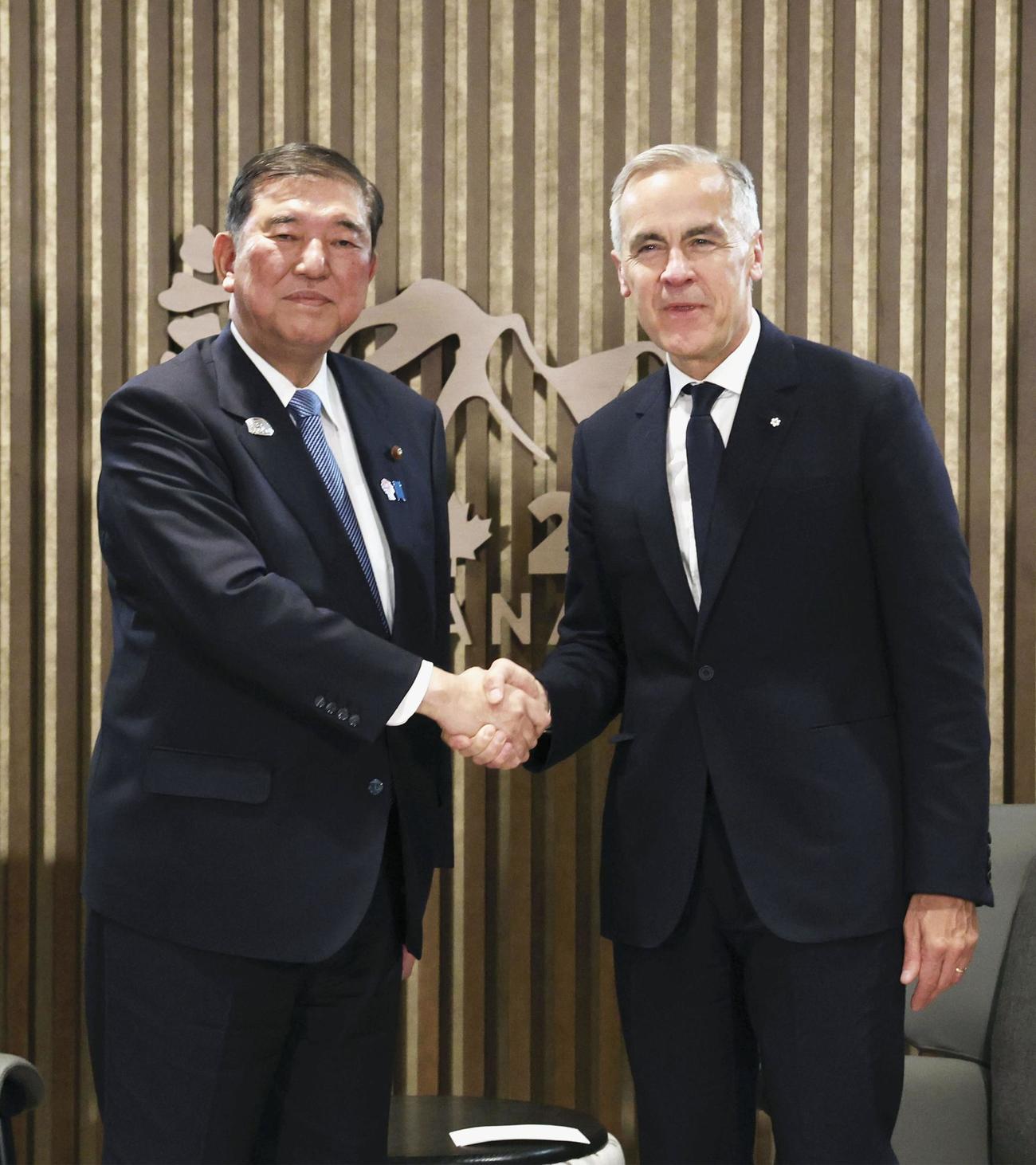 会談前に握手する石破首相（左）とカナダのカーニー首相＝16日、カナダ西部カナナスキス（代表撮影・共同）