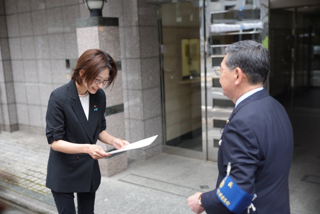 事務所がないため道ばたで当選証書を受け取る佐藤沙織里氏（Xから）
