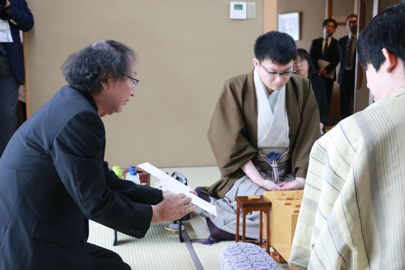 王位戦7番勝負第2局、永瀬拓矢九段（左）の封じ手の封筒を開封する立会人の福崎文吾九段（日本将棋連盟提供）