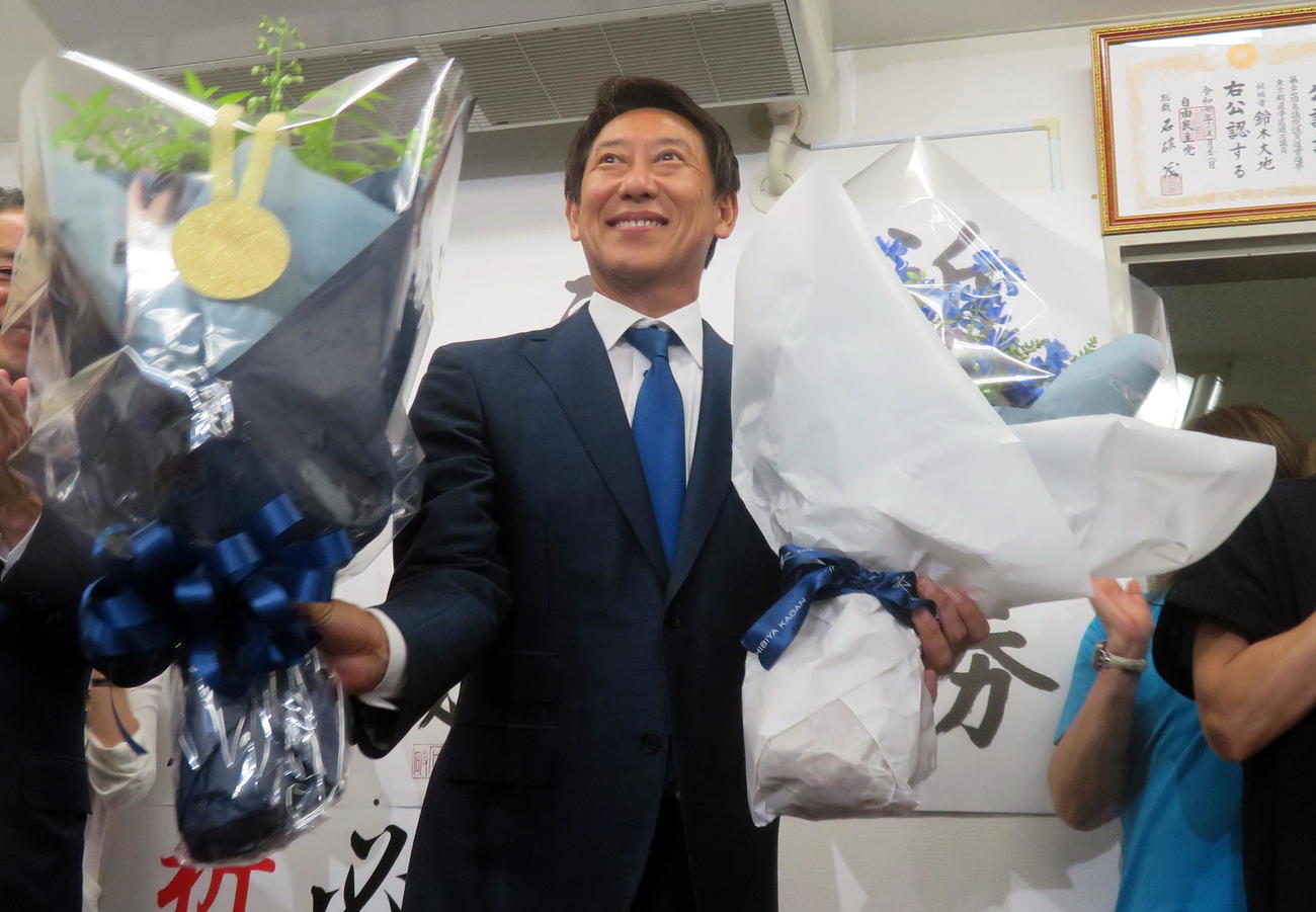 参院選で初当選し、両手に花束を抱えて笑顔を見せる鈴木大地氏（撮影・鎌田直秀）