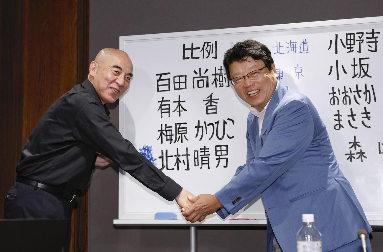 比例代表で当選を決めた北村晴男氏（右）と握手する日本保守党の百田代表（共同）