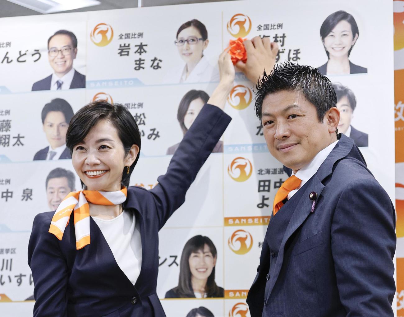 比例代表で当選を決めた梅村みずほ氏（左）と花を付ける参政党の神谷代表（共同）