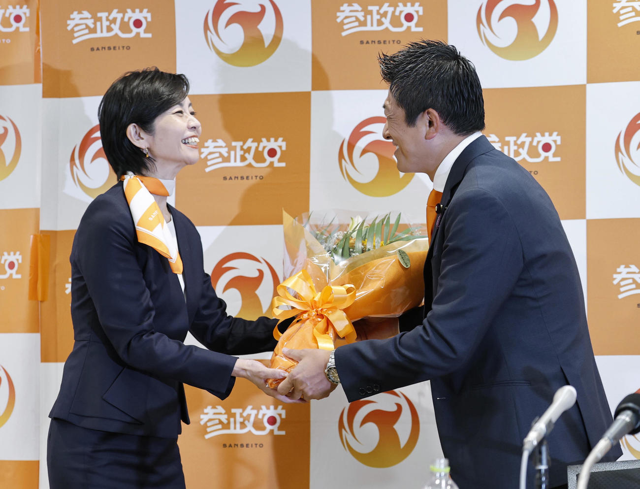比例代表で当選を決めた梅村みずほ氏（左）に花束を渡す参政党の神谷代表（共同）