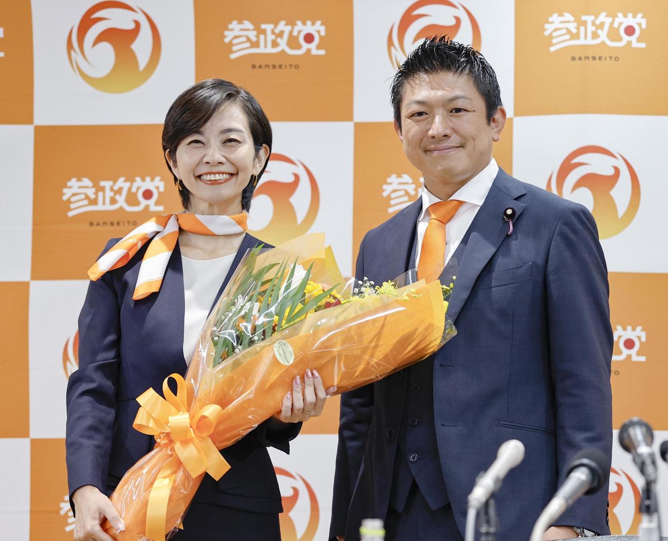 比例代表で当選を決めた梅村みずほ氏（左）に花束を渡した参政党の神谷代表（共同）