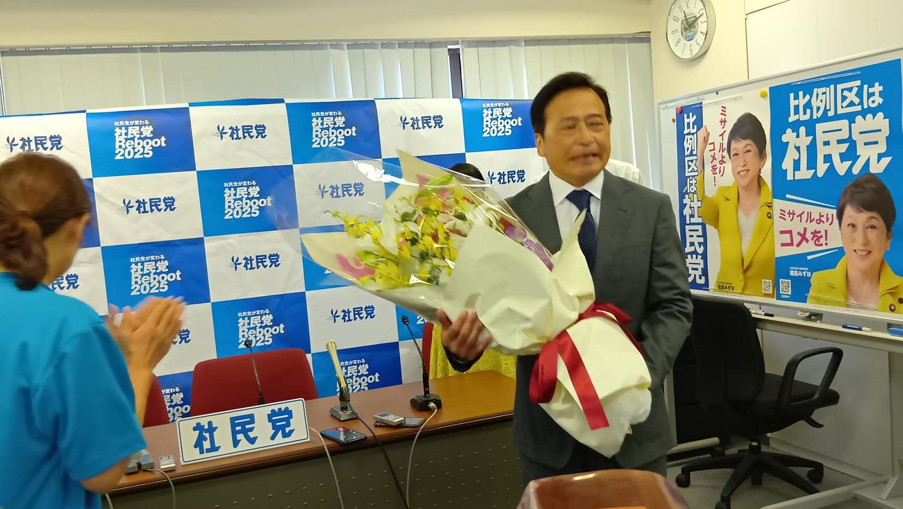 社民党本部で花束を贈られ感無量のラサール石井氏