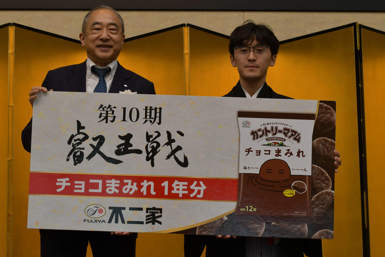 主催の不二家・河村宣行社長（左）から副賞として渡された「チョコまみれ」1年分の目録を手にする伊藤匠叡王（右）