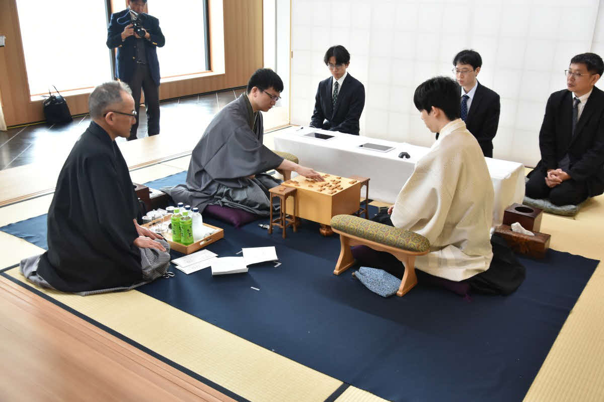 立会人の島朗九段（左）が示した封じ手を永瀬拓矢九段（中央）が指して王位戦第3局2日目が再開（右は藤井聡太王位、日本将棋連盟提供）