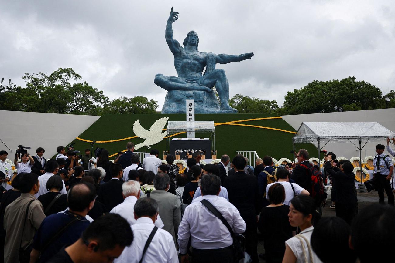 長崎平和祈念像の前で祈りを捧げる参加者たち（ロイター）
