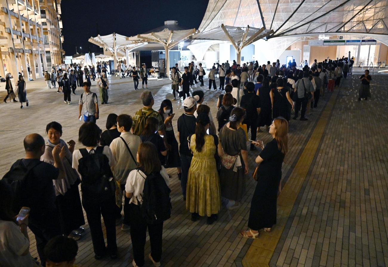 大阪メトロ中央線が運転見合わせとなり、休憩用に開放されたパビリオンに並ぶ人たち＝14日午前0時49分（共同）