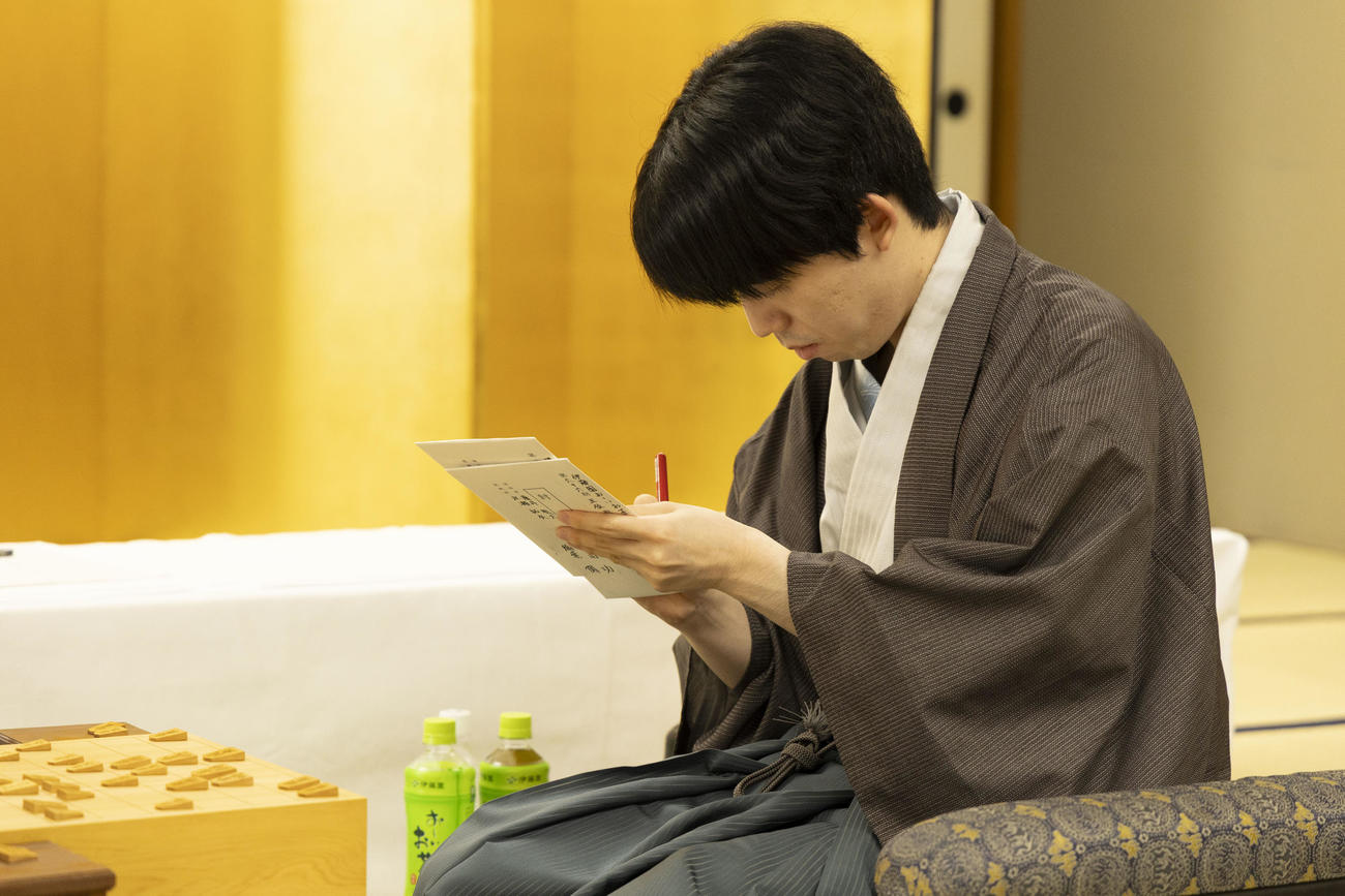 第66期王位戦7番勝負第4局、永瀬拓矢九段の封じ手の封筒にサインする藤井聡太王位（日本将棋連盟提供）