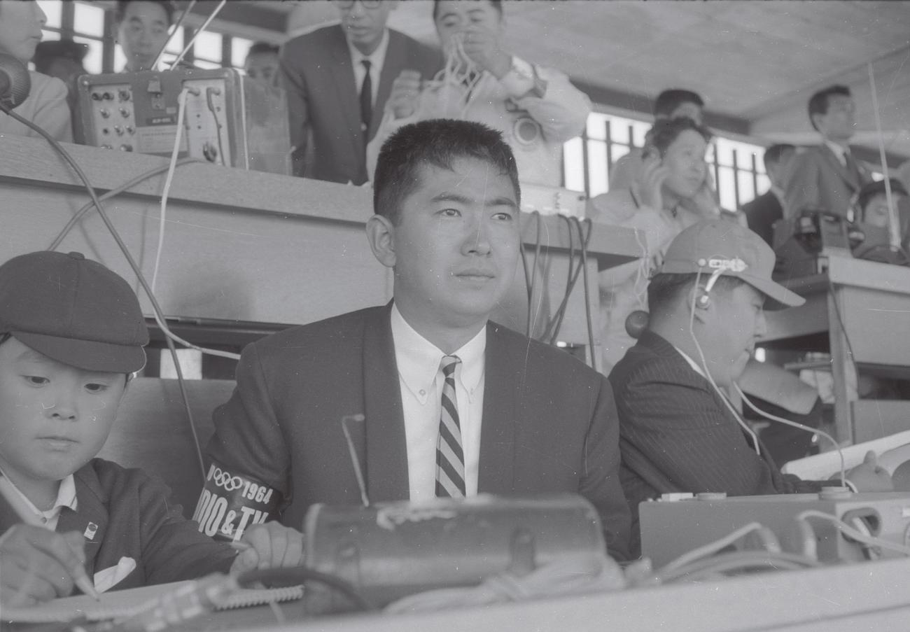 64年、記者席で開会式を見る石原慎太郎氏、左は長男伸晃氏