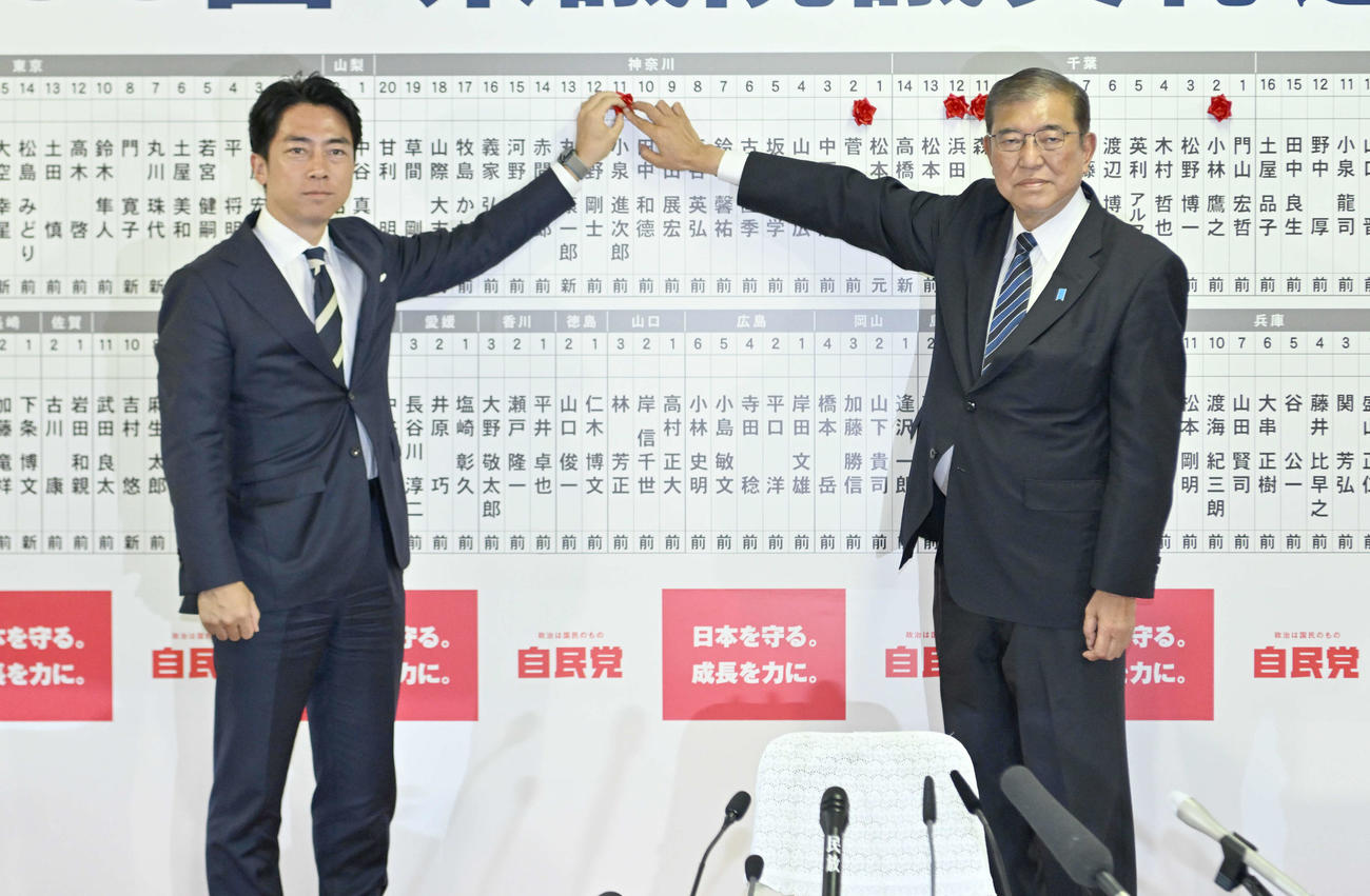 第50回衆院選　当確者の名前にバラを付ける自民党の小泉進次郎選対委員長（左）と総裁の石破茂首相（2024年10月27日撮影）