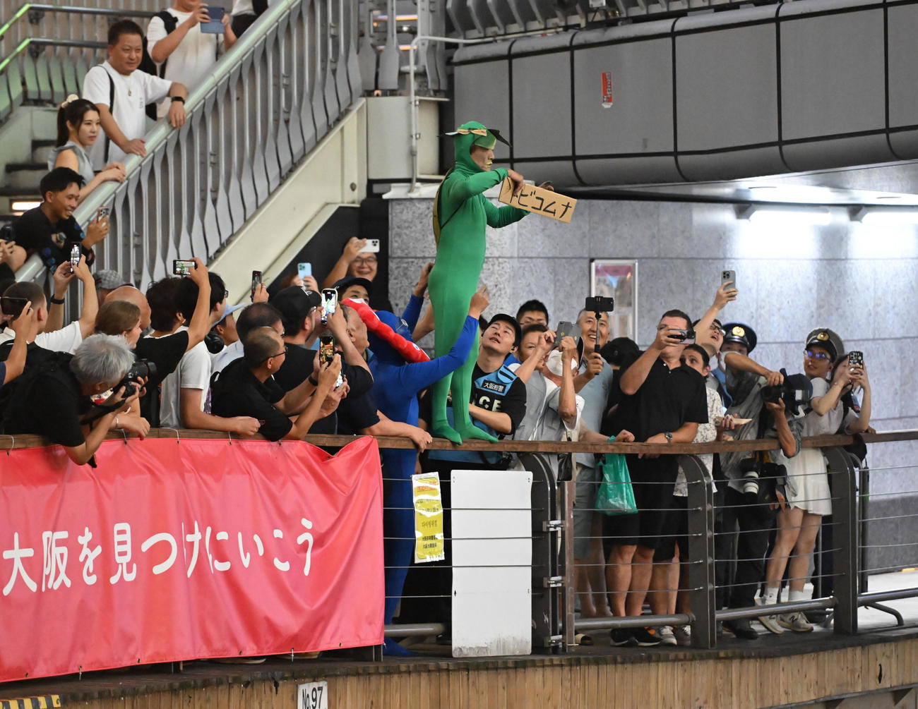 阪神のリーグ優勝に喜ぶも、「トビコムナ」と書かれたボードを持つカメの衣装を着たファン（撮影・和賀正仁）