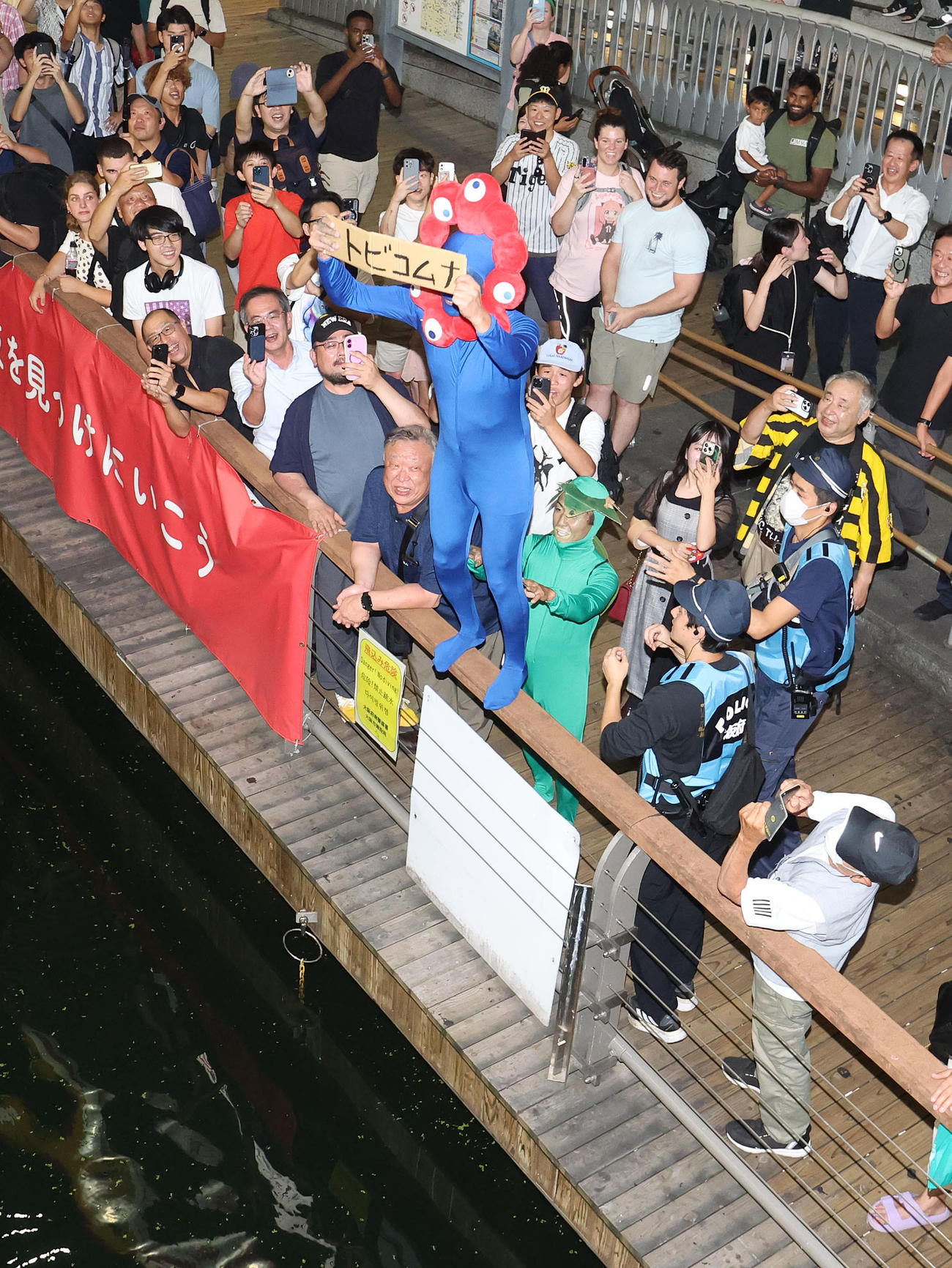 トビコムナとボードを持つミャクミャクのコスプレをしたファン（撮影・白石智彦）