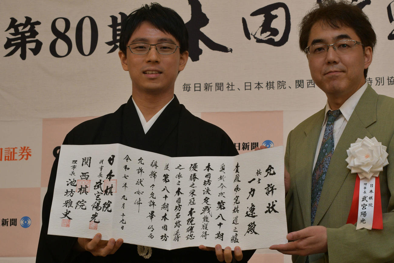 一力遼本因坊（左）は就位式で日本棋院の武宮陽光理事長（右）から允許（いんきょ）状を授与される