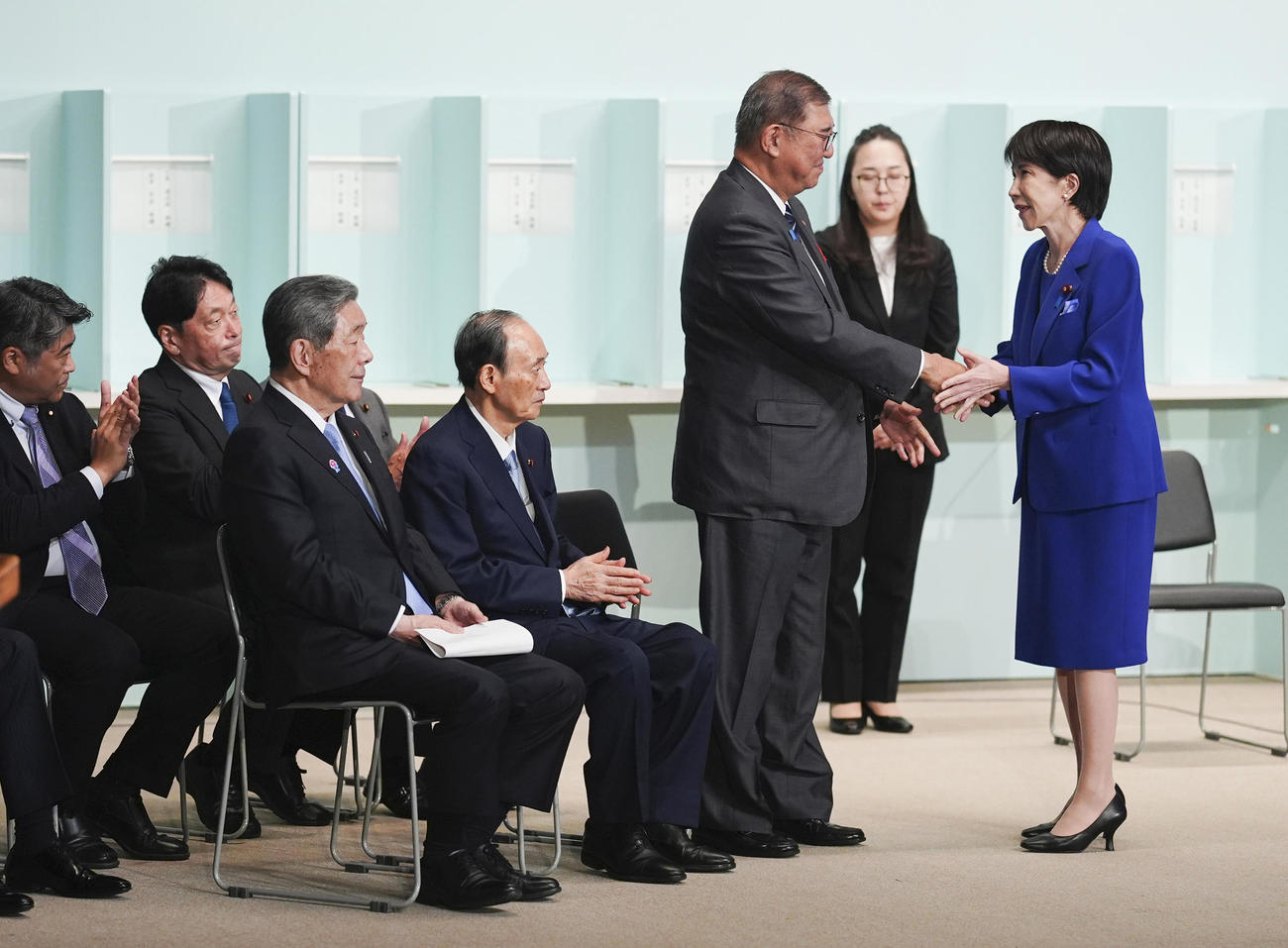 自民党総裁選後に開かれた両院議員総会で握手する高市早苗新総裁（右端）と石破首相（共同）