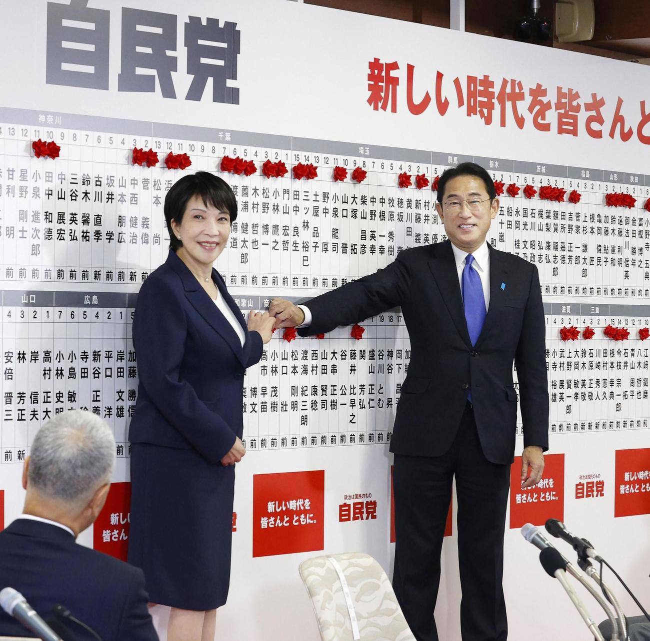 2021年10月、自民党本部の開票センターで、当選を決め総裁の岸田首相（右）と自身の名前に花を付ける高市政調会長（共同）