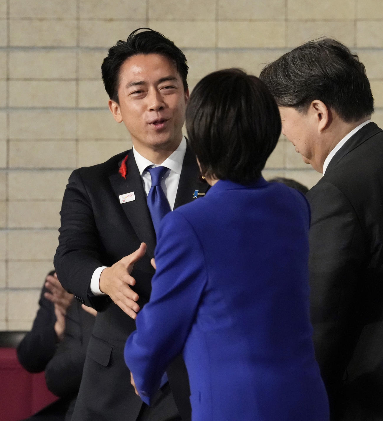 自民党の新総裁に選出された高市早苗氏（手前）と握手を交わす小泉進次郎氏（共同）