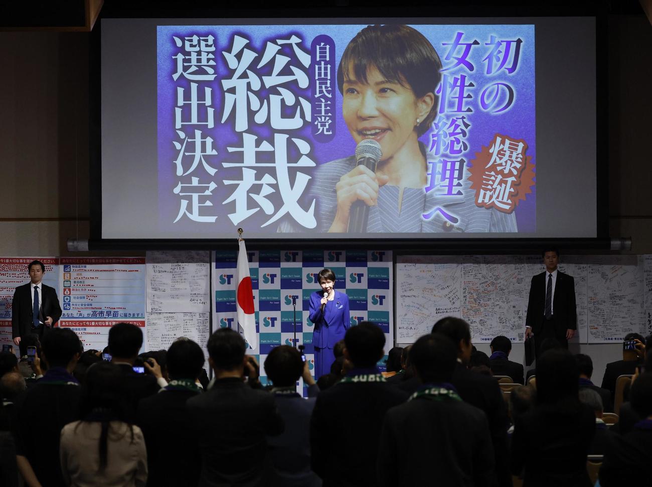 女性初の自民党総裁に選出され、陣営の報告集会であいさつする高市早苗氏（中央）（共同）