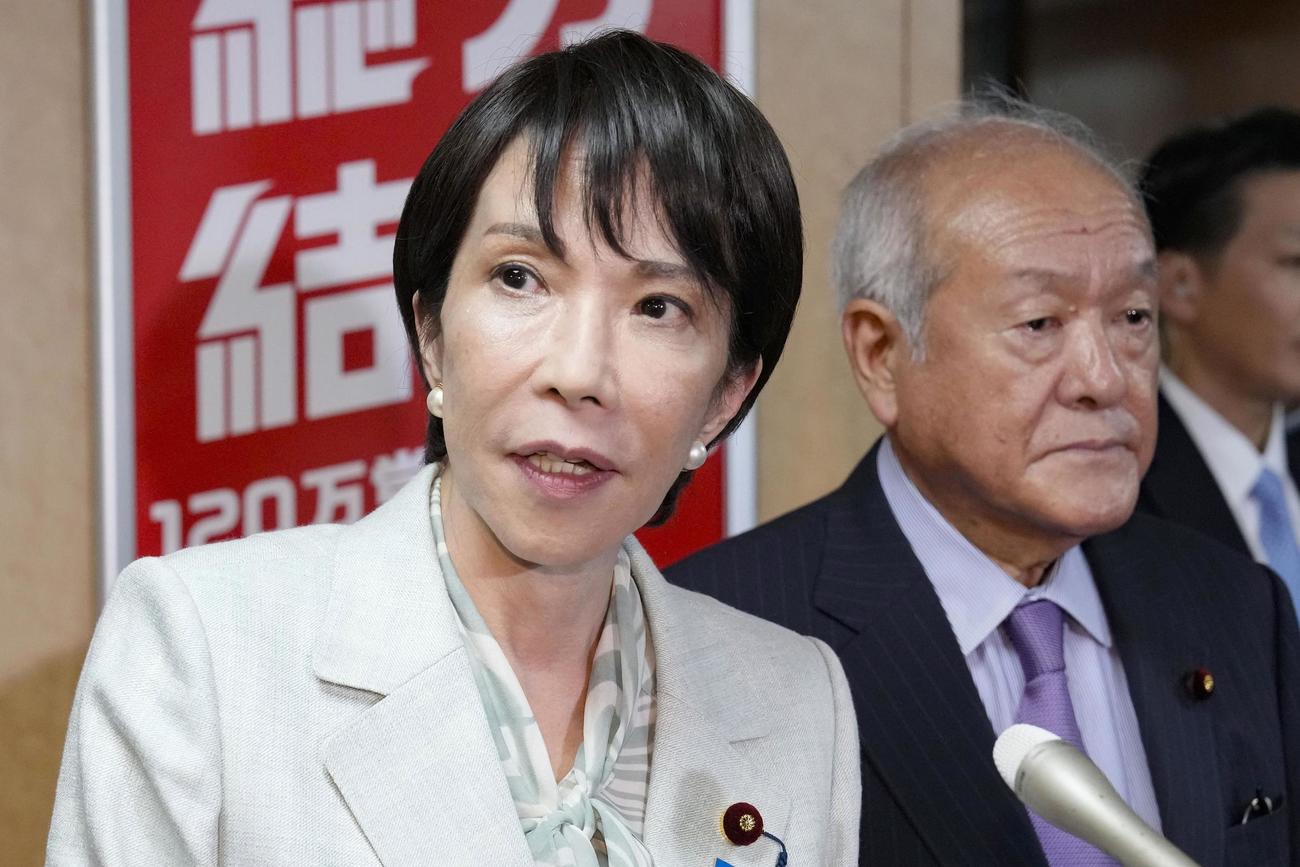 公明党幹部との会談後、自民党本部で記者団の取材に応じる高市総裁。右は鈴木幹事長（共同）