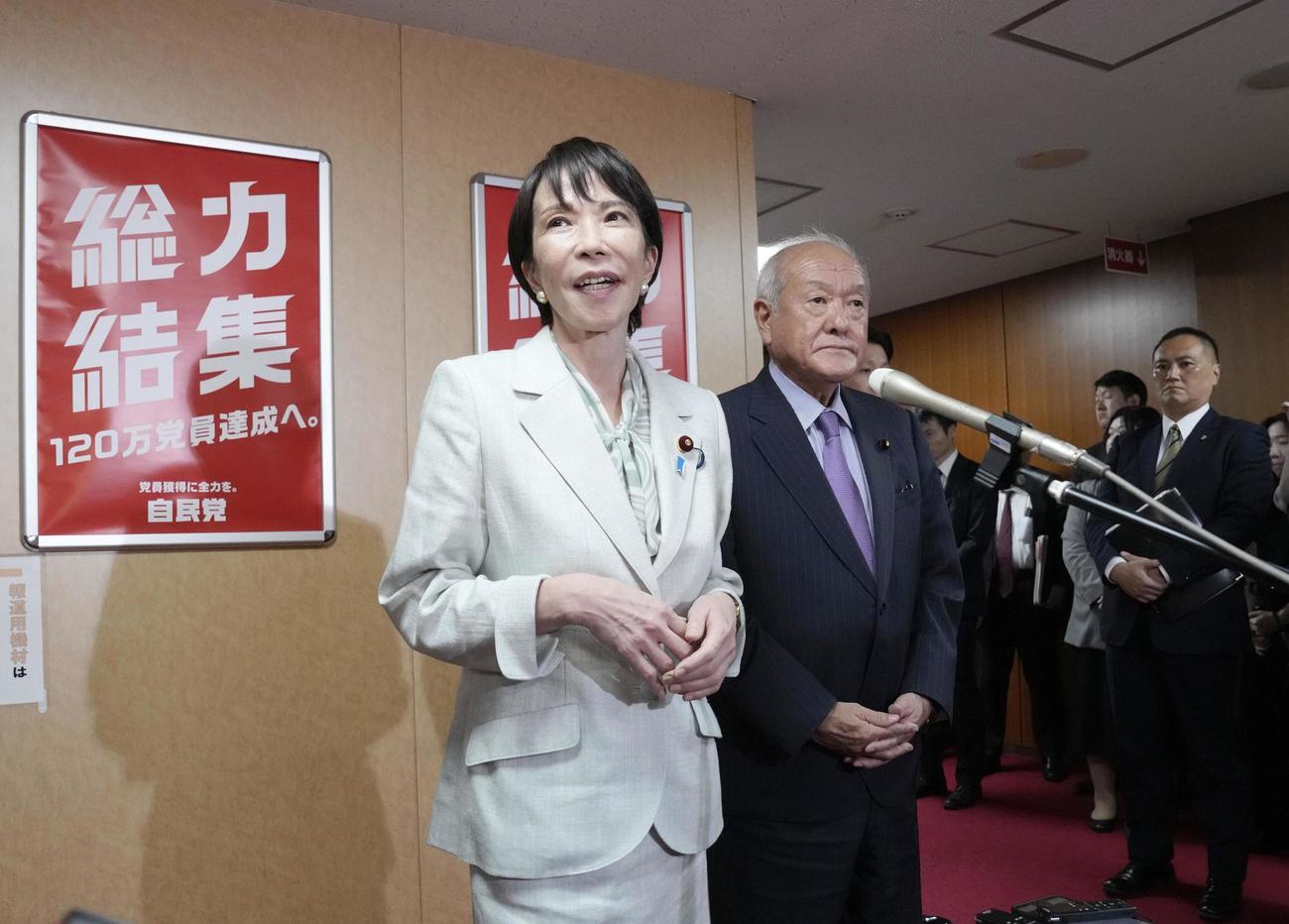 自民党本部で記者団の取材に応じる高市総裁。右は鈴木幹事長（共同）