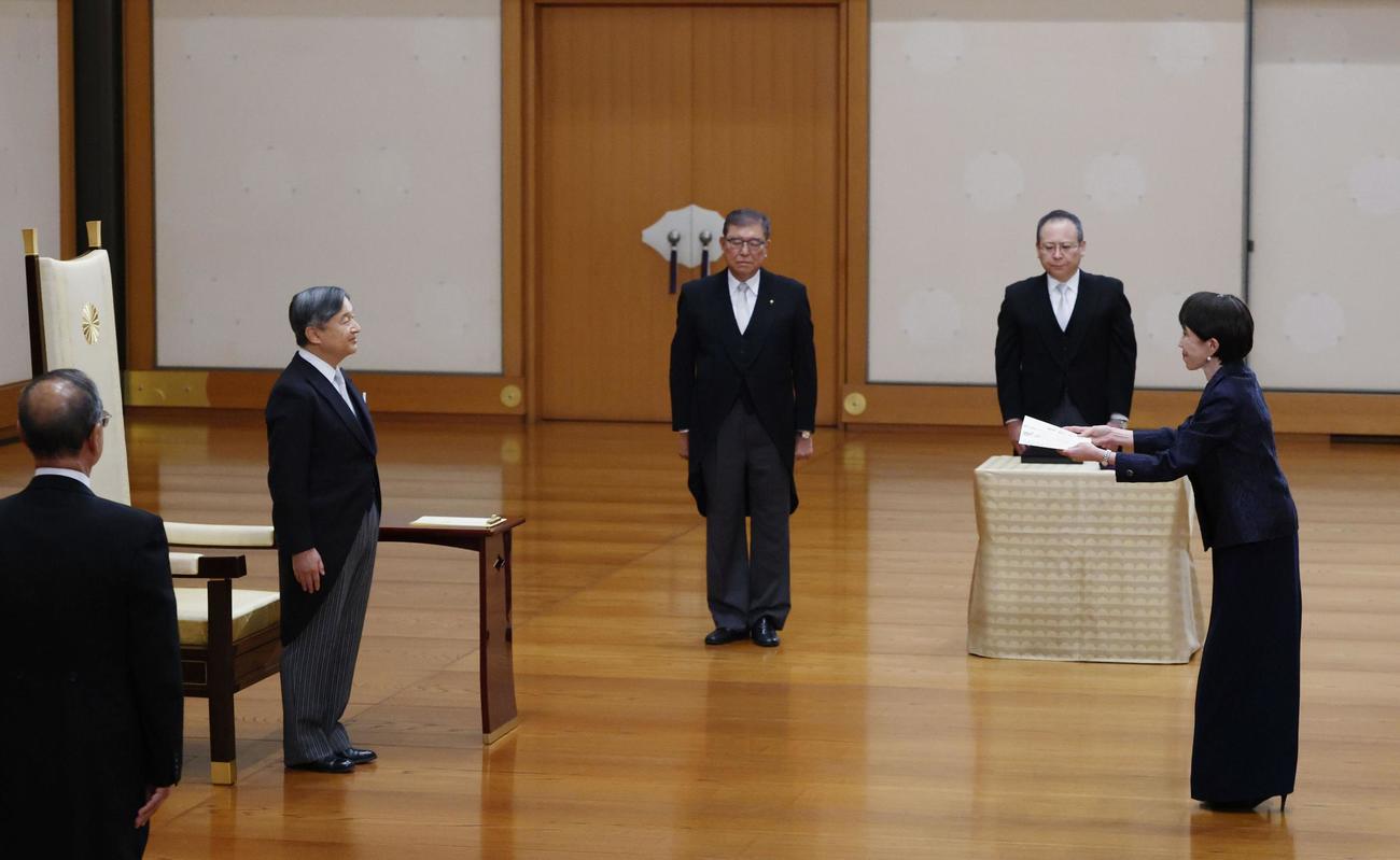 天皇陛下から任命を受ける高市早苗首相。中央は石破茂前首相（共同）
