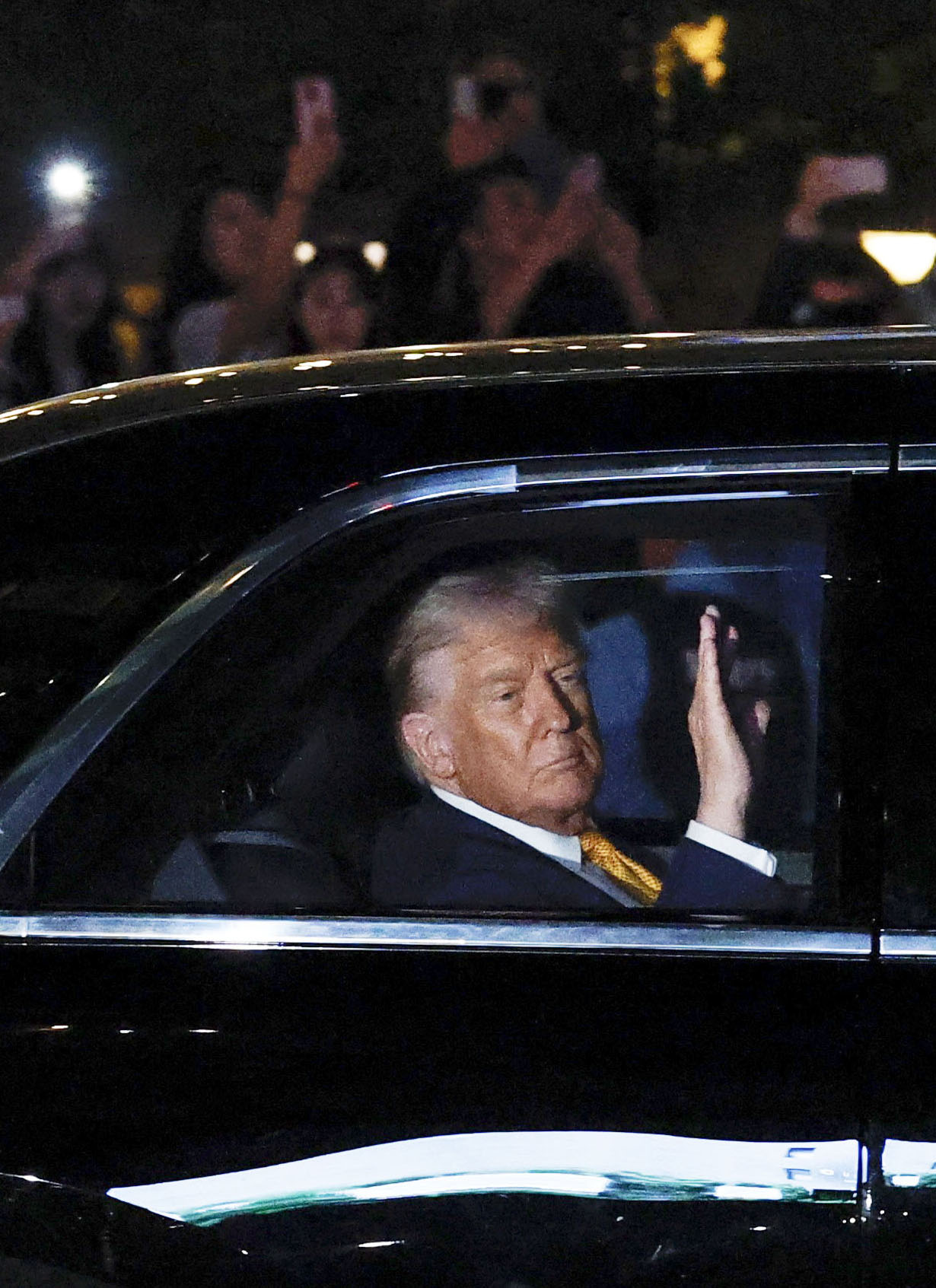 米大統領専用車から沿道に手を振るトランプ大統領＝27日夜、東京都港区