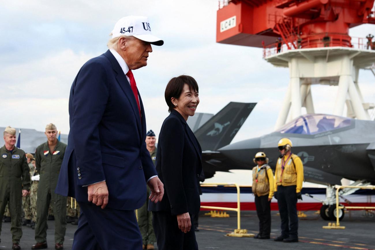 米原子力空母「ジョージ・ワシントン」に乗り込んだパンツスーツ姿の高市早苗首相（右）とトランプ米大統領（ロイター）