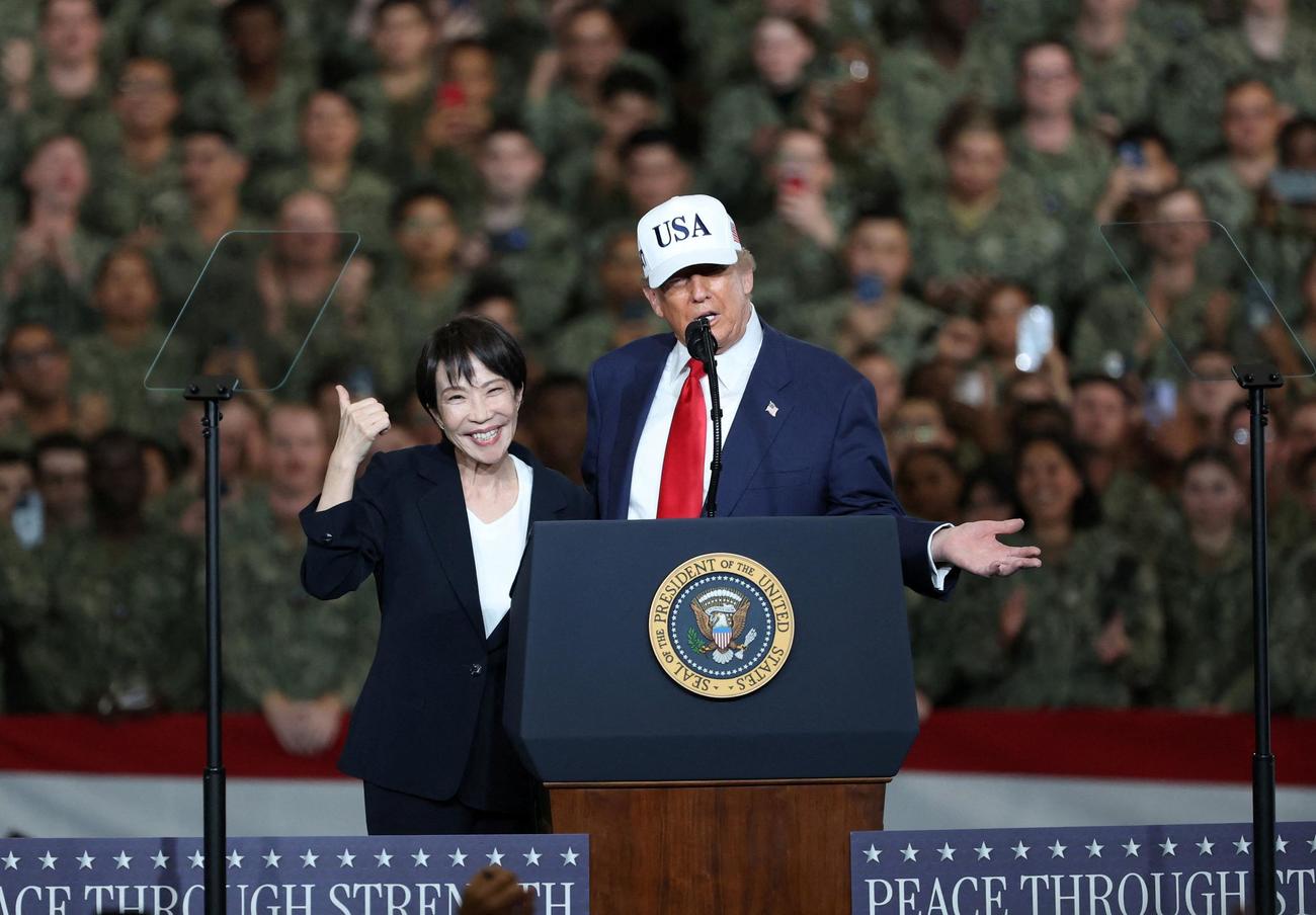 空母ジョージ・ワシントン艦上で、ドナルド・トランプ米大統領が演説している中、ポーズ決める高市早苗首相（ロイター）