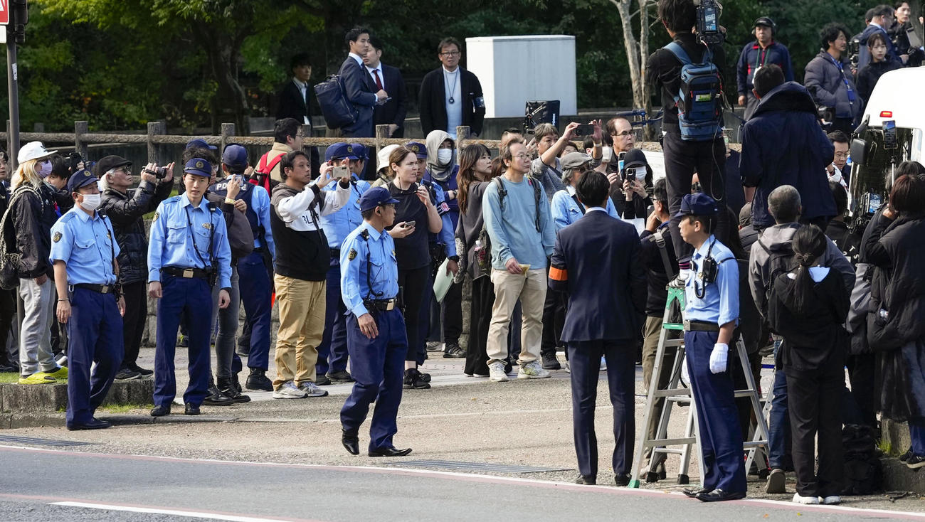 奈良地裁前に集まった大勢の人たちと周囲を警戒する警察官＝28日午後0時57分
