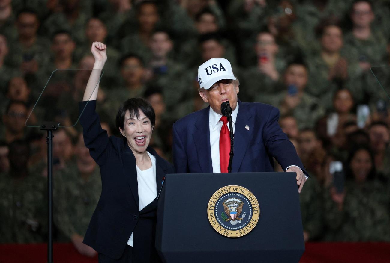 米軍横須賀基地で右手拳を上げて弾ける様子の高市早苗首相とスピーチするトランプ米大統領（ロイター）