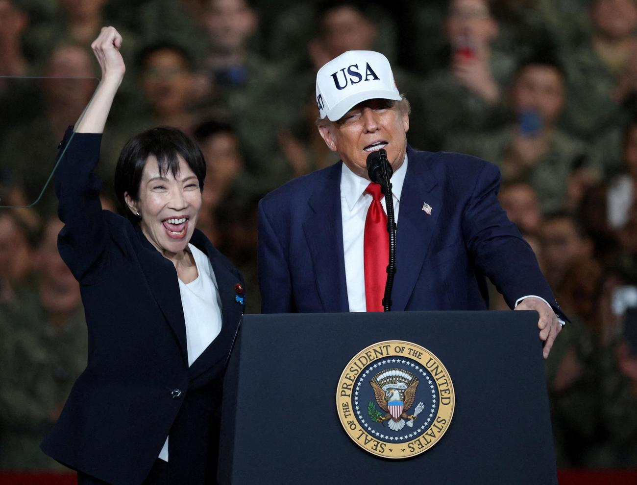 米軍横須賀基地でスピーチするトランプ米大統領の隣で右手拳を突き上げ、はじける高市早苗首相（ロイター）