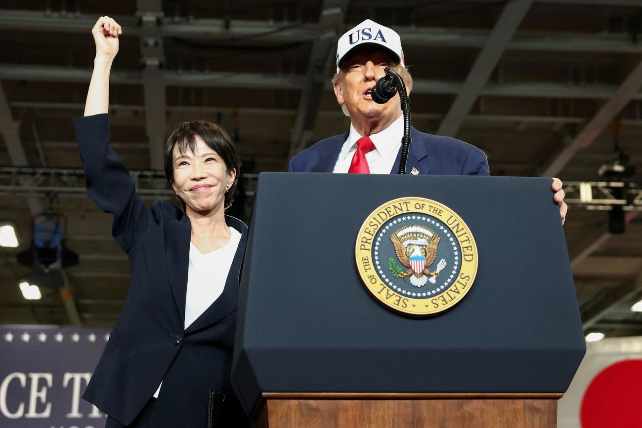 米軍横須賀基地で右手拳を上げて弾ける様子の高市早苗首相とスピーチするトランプ米大統領（ロイター）
