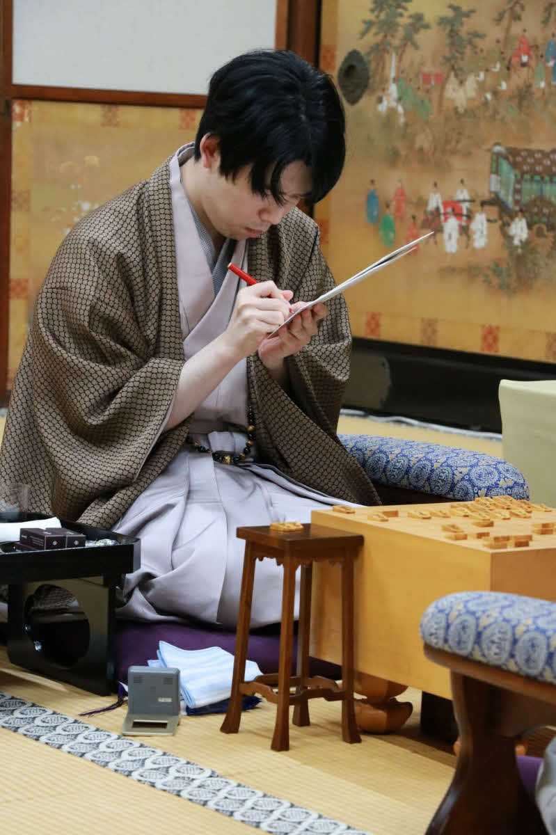 佐々木勇気八段の封じ手が入った封筒にサインする藤井聡太竜王（日本将棋連盟提供）
