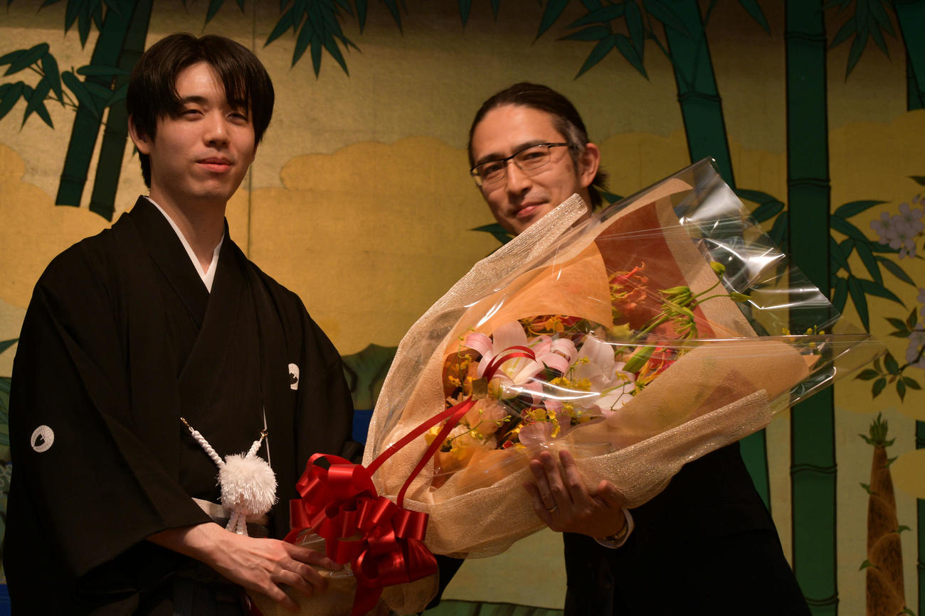 藤井聡太王位（左）は就位式で木村草太東京都立大教授（右）から花束を贈呈される