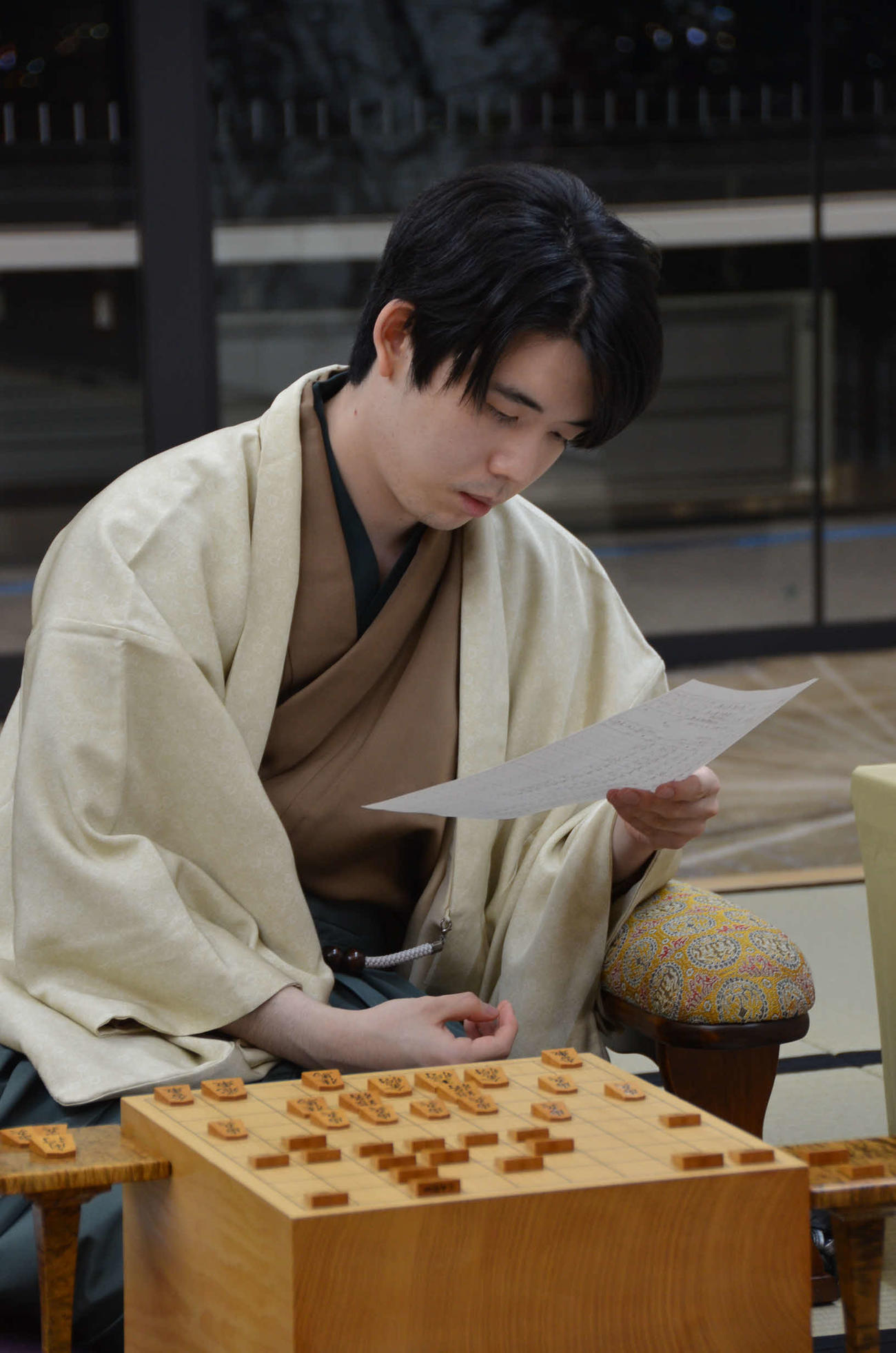1日目を終え、記録用紙をチェックする藤井聡太竜王（日本将棋連盟提供）