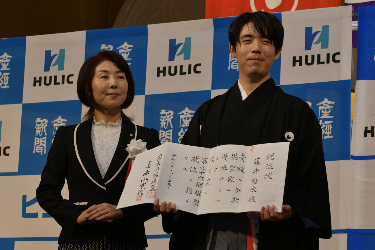 日本将棋連盟・清水市代会長（左）から渡された就位状を手にする藤井聡太棋聖