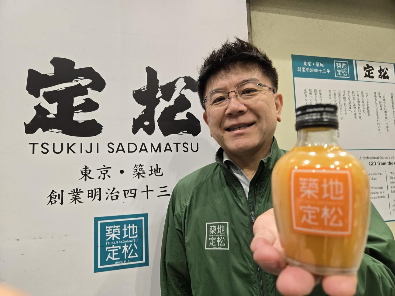 ストレートみかんジュースを持って笑顔の牧泰利社長（撮影・寺沢卓）