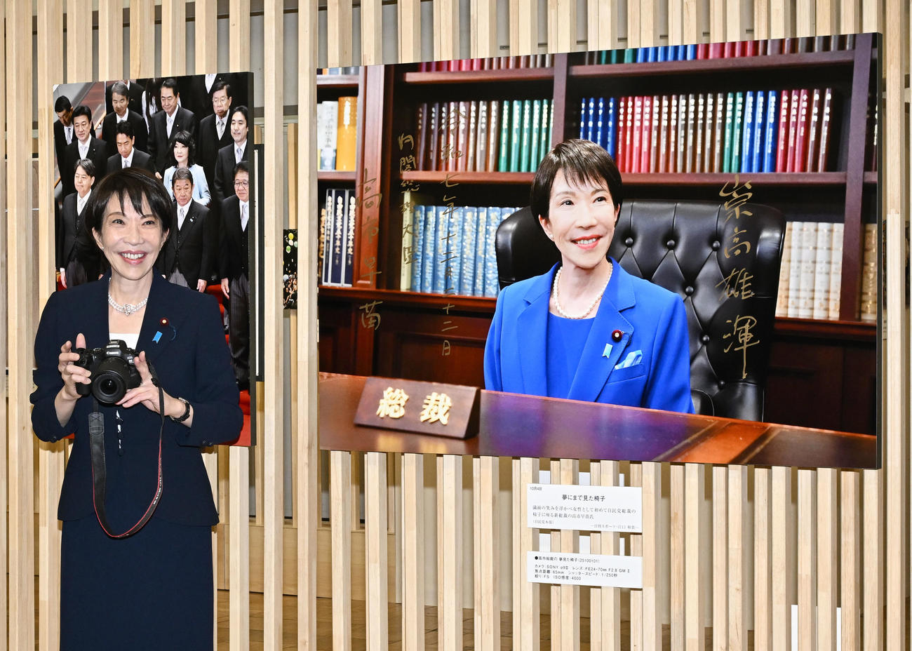 「2025年報道写真展」の自身の写真の前でカメラを手にする高市首相（撮影・千葉一成）