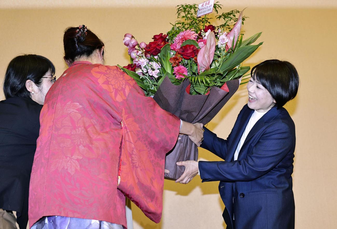 前橋市長選で再選を決め、花束を受け取る小川晶氏（右）＝12日夜、前橋市（共同）